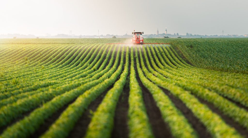 Tractor spraying pesticides at soy bean fields